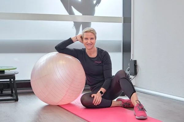 Businessfotografie in Zug: Pilatestrainerin sitzt auf einer Matte neben einem Gymnastikball