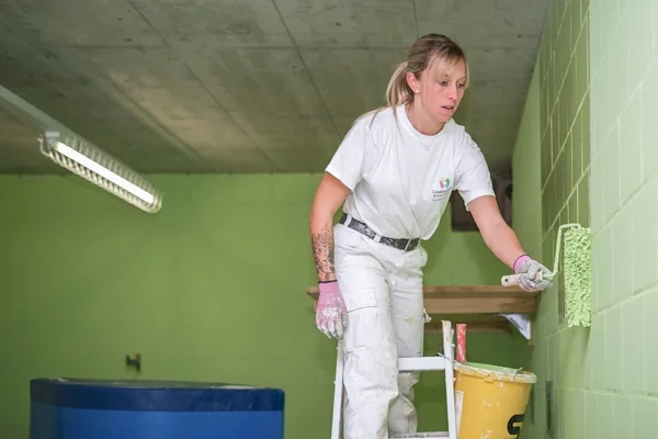Handwerkerfotografie in Zug: Malerarbeiten auf der Leiter an einer grünen Wand