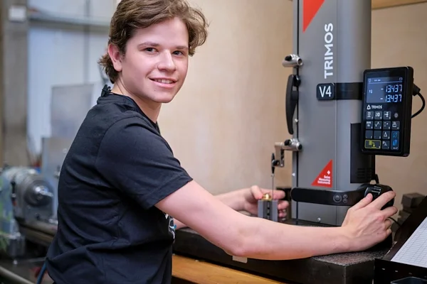 Mitarbeiterfoto in Zug: junger Mitarbeiter an einem Messgerät in der Werkstatt