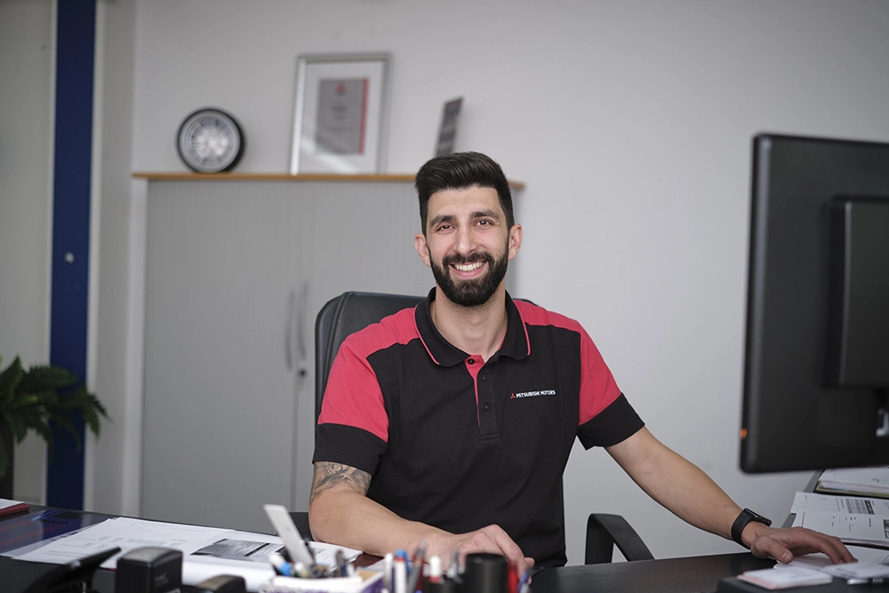 Mitarbeiterportrait in Zug: Mitarbeiter im rot-schwarzen Poloshirt am Schreibtisch im Büro