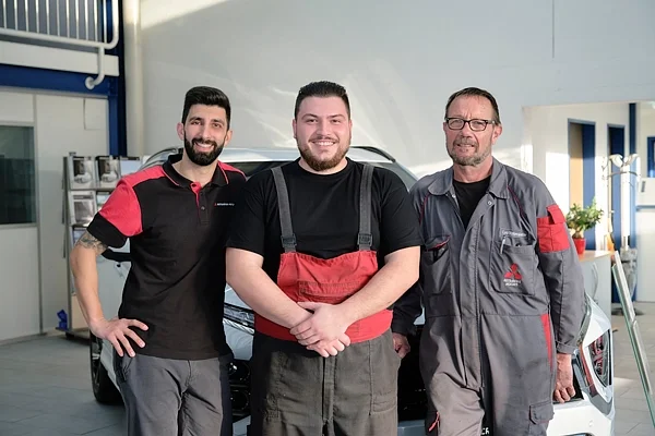 Teamfotografie in Zug: drei Mitarbeiter einer Garage stehen in der Werkstatt vor einem Auto